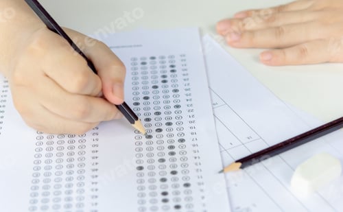 Preview: Students hand holding pencil writing selected choice on answer sheets