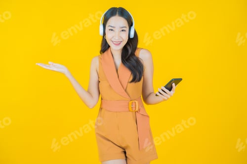 Preview: Smiling Woman with Headphones Presenting on Yellow Backdrop