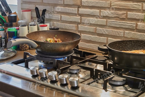 Preview: rying pans with fried potatoes, chestnuts, parsley, parmesan on gas stove in the kitchen