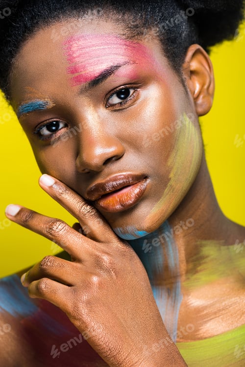 Preview: Charming african american woman with colorful body art isolated on yellow