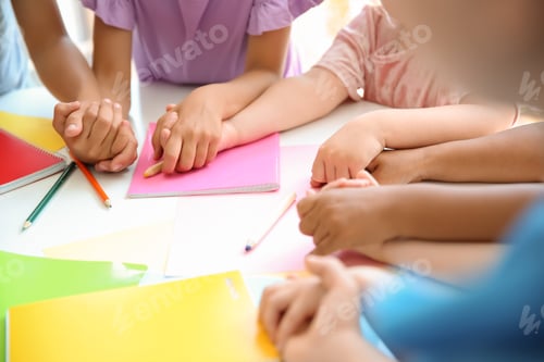 Preview: Little children holding hands at table, closeup. Unity concept