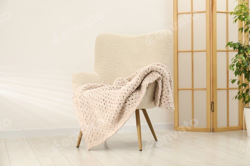 Preview: Comfortable armchair with woolen blanket in room