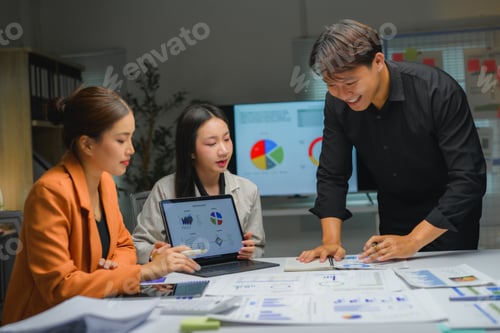 Preview: Asian business team analyzing financial data on laptop and paperwork at office meeting
