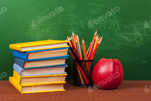 Preview: Red apple on a pile of books, paper and pencil on the desk