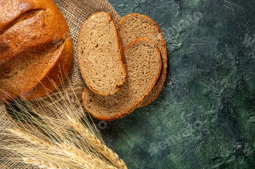 Preview: Close up view of whole and cut dietary black bread and spikes on brown towel on dark colors