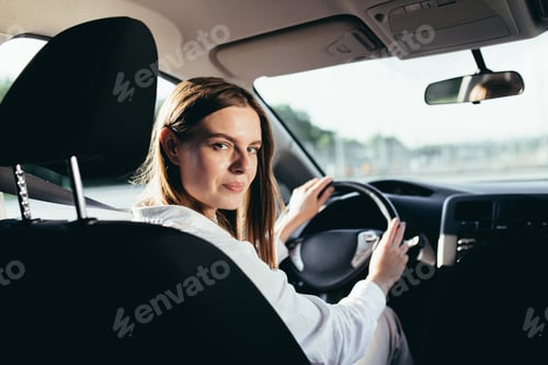 Preview: Portrait of a successful woman driving a car, smiling rejoicing and looking at the camera