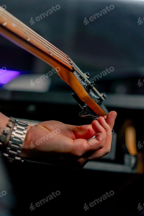 Preview: close up in the recording room equipment the sound of music handsome young guy tunes a guitar plucks