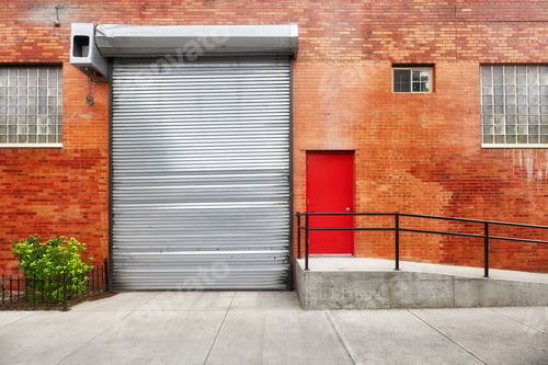 Preview: Empty street with brick wall building with automatic rolling shutter.