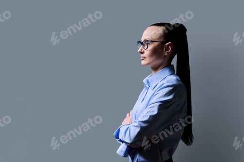 Preview: Profile view of 30s serious business woman, gray background, copy space