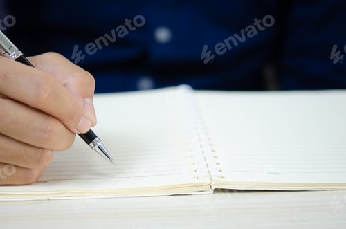 Preview: close up holding a pen and writing at the notebook.