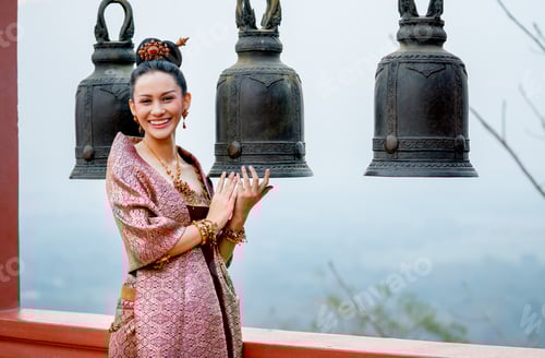 Preview: Portrait of beautiful Asian woman wear Thai traditional dress stand in front of bell in area of temp