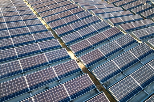 Preview: Aerial view of many photo voltaic solar panels mounted of industrial building roof.