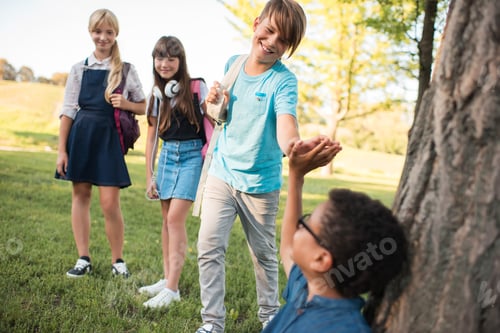 Preview: smiling multiethnic teenagers meeting and giving high five in park