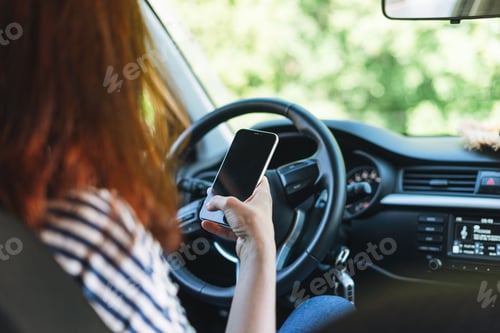 Preview: Young woman using mobile phone in car