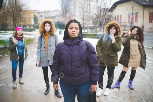 Preview: group of young multiracial women smoking cigarette in the street