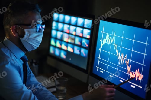 Preview: Businessman with computer sitting at desk, working late in office. Financial crisis concept