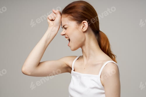 Preview: beautiful woman in white t-shirt touching face with hands on gray background health problems