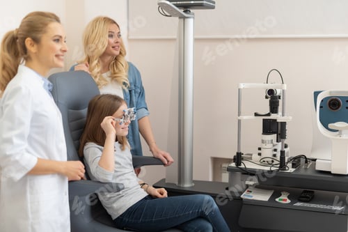 Preview: Side View Portrait Of Adorable Little Girl In Ophthalmic Testing Glasses Sitting In Chair While Her