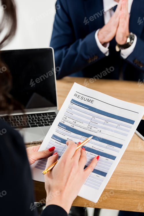 Preview: selective focus of recruiter holding resume and pencil near man gesturing in office