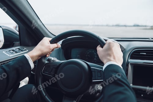 Preview: Drive carefully! Close up of man keeping hands on the steering wheel while driving a car