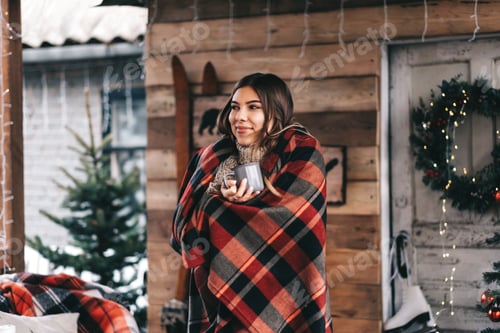 Preview: Young caucasian happy woman in a plaid is drinking a hot drink