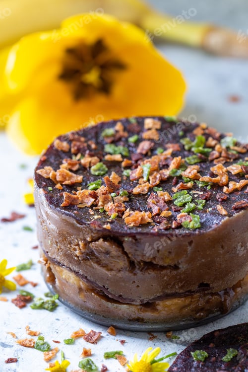 Preview: Vertical shot of a raw cake with bananas and chocolate decorated with flowers on the table