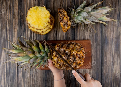 Preview: top view of woman hands cutting pineapple with knife on cutting board with sliced pineapple