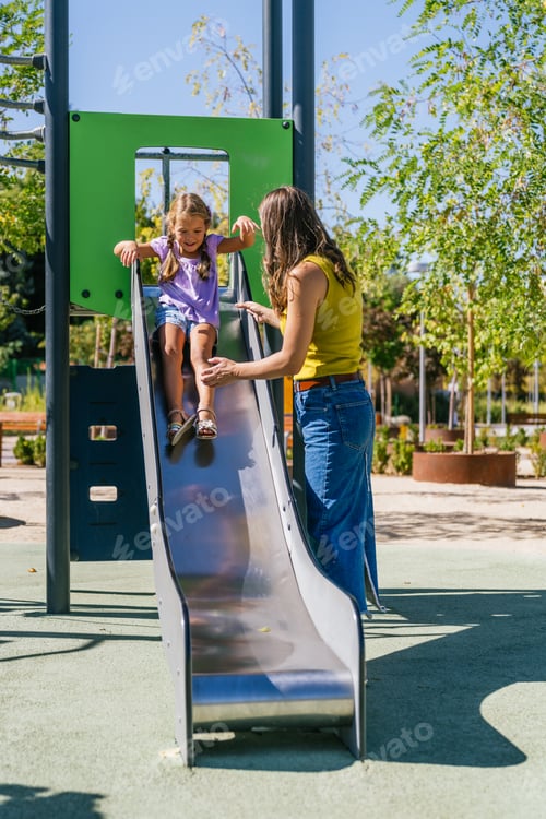 Preview: Mother playing with daughter on playground slide