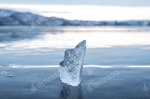 Preview: A transparent icicle on the frozen surface of Lake Baikal in winter against the sky. Close-up.