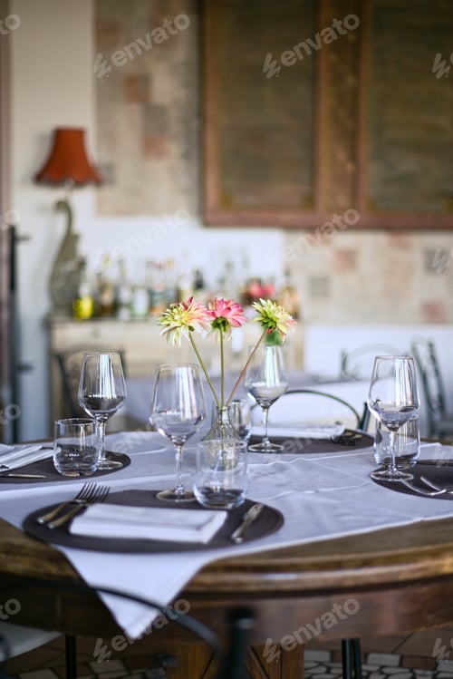 Preview: Charming restaurant table set for dinner with flowers and wine glasses