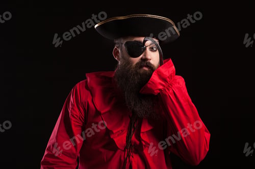 Preview: Attractive bearded man in a pirate costume for carnival touching his eye patch with his arm hook