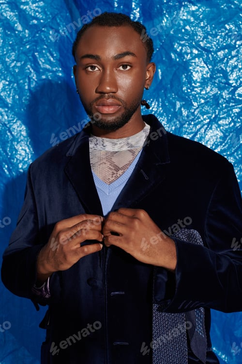Preview: Elegant young man posing confidently in front of a striking blue backdrop