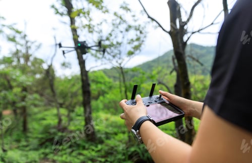 Preview: People remote control a flying drone in summer forest