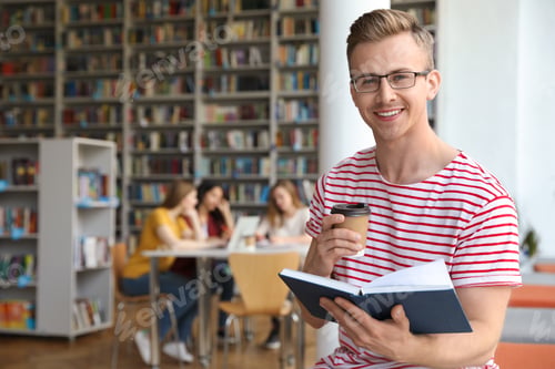 Preview: Young man with book and drink in library. Space for text