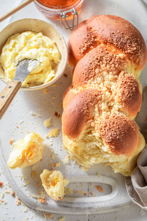 Preview: Fresh and hot golden challah on white table.