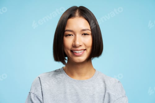 Preview: Beautiful asian woman with stylish hairstyle looking at camera standing isolated on blue background