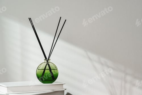 Preview: Aromatic Reed Diffuser on White Books With Shadows Playing on the Wall
