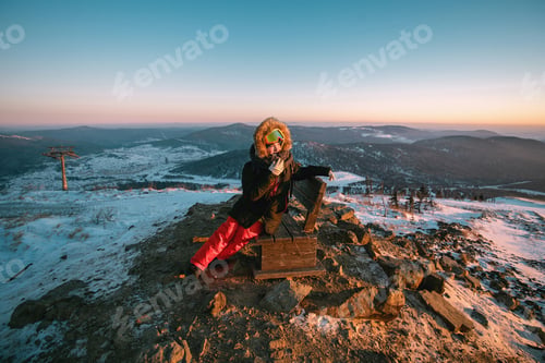Preview: Woman in ski clothing outdoors on a view point on a mountain in sunny winter day