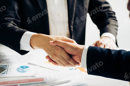 Preview: Entrepreneurs collaboration deal shaking hands in a modern office and financial paper graph on desk.