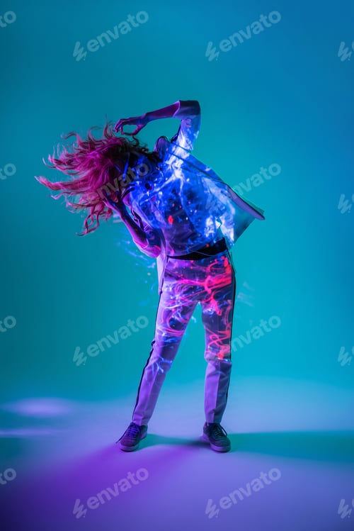 Preview: Woman enjoying music with smartphone and jumping in neon light
