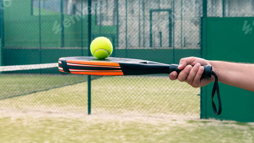 Preview: One caucasian man with the ball on top of the padel racket at green court grass