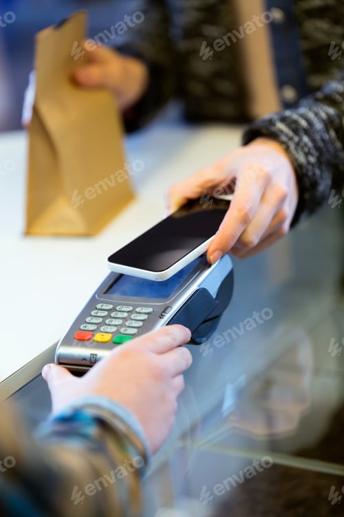 Preview: Customer using her smartphone to make mobile payment with electr