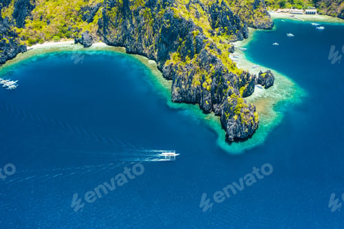 Preview: Aerial drone view of white boat in open sea, tropical island and beach of Miniloc Island. El Nido