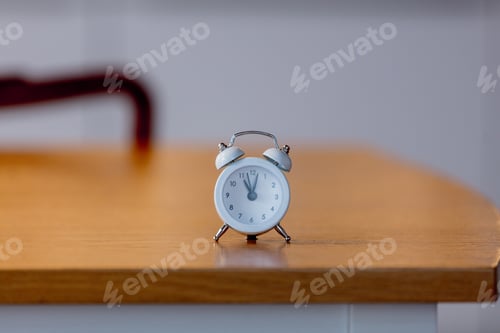 Preview: white little alarm clock on a table