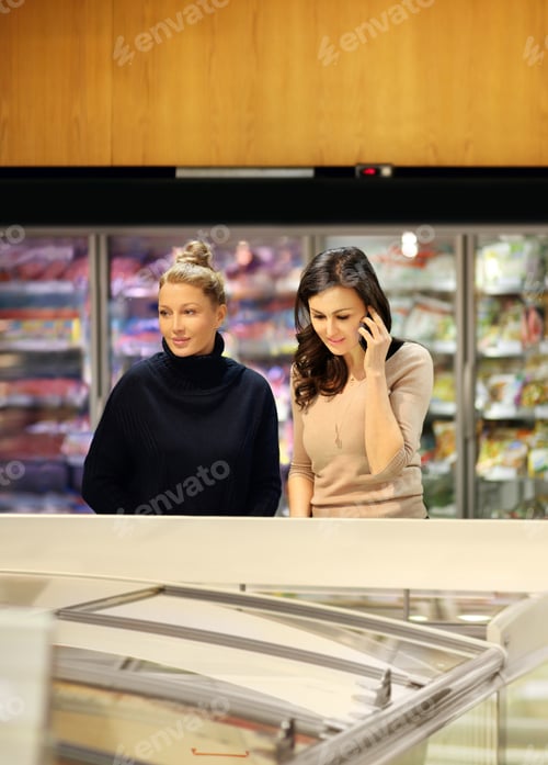 Preview: Two Women Choosing Frozen Food From A Supermarket Freezer