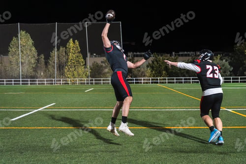 Preview: American football player catching ball during night game