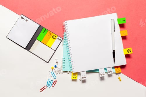 Preview: Notebook and colorful stationery items on a divided white and pink background