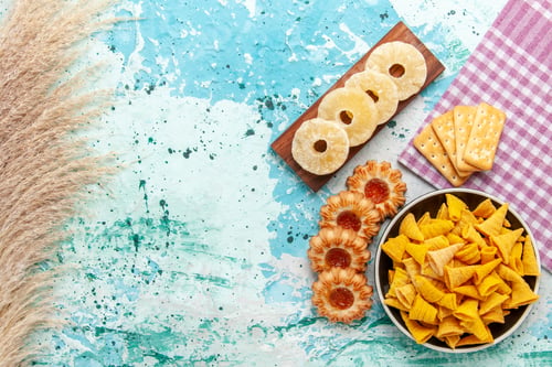 Preview: top view little spicy chips with crackers dried pineapple rings and cookies on light-blue background