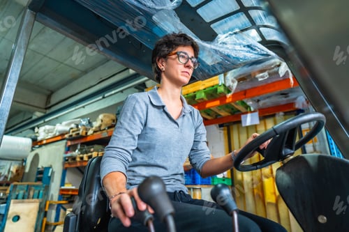 Preview: Concentrated woman working with forklift in a warehouse