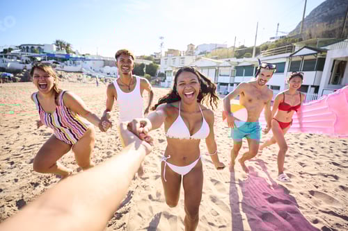 Preview: POV holding hand of a group of young multiracial people in swimwear joyfully running on the beach